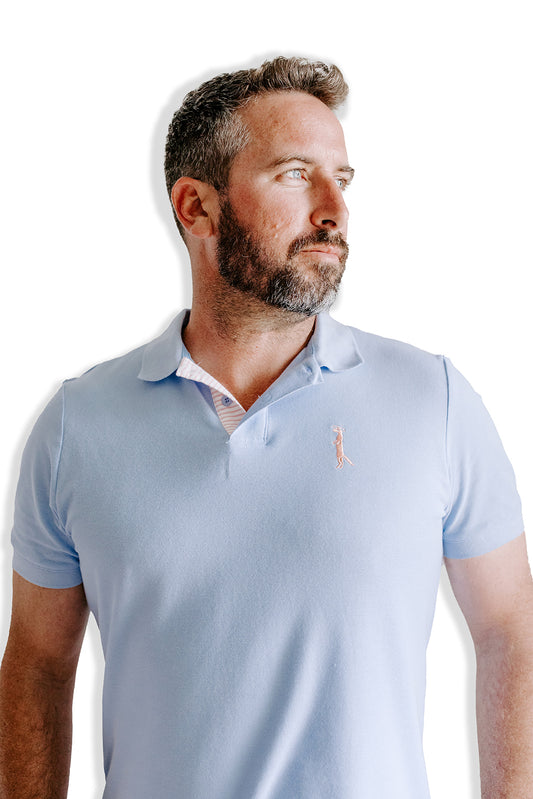 Beautiful knit polo in our signature Chambray blue with peach and white striping on the inside collar. Embroidered with our Saint Mongoose in peach on the left chest.  100% cotton