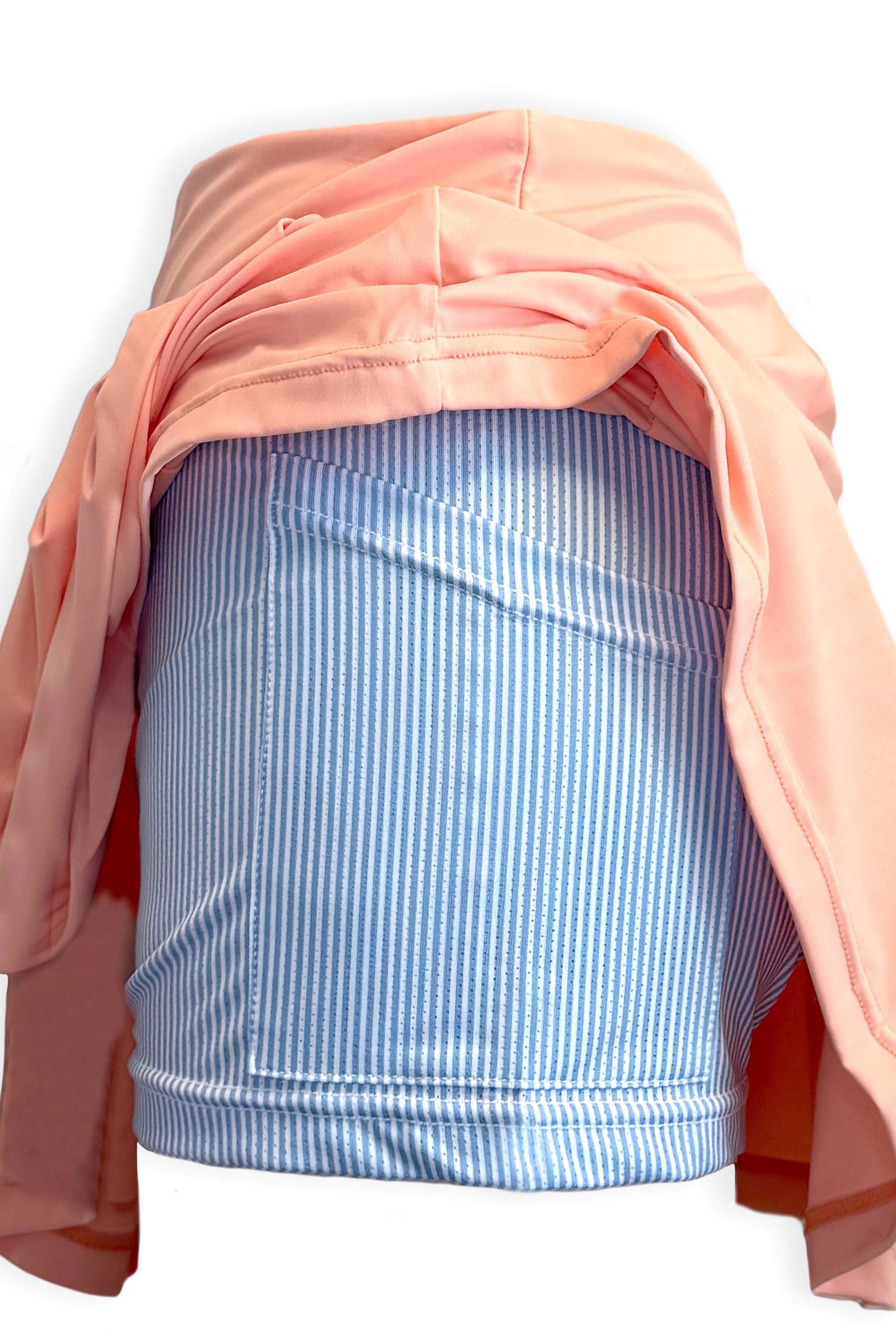 Peach pleated tennis skirt in soft, stretchy and sustainable fabric. Built in shorts with pockets in blue and white seersucker fabric with the brand's Mongoose logo printed on the back of the waist.